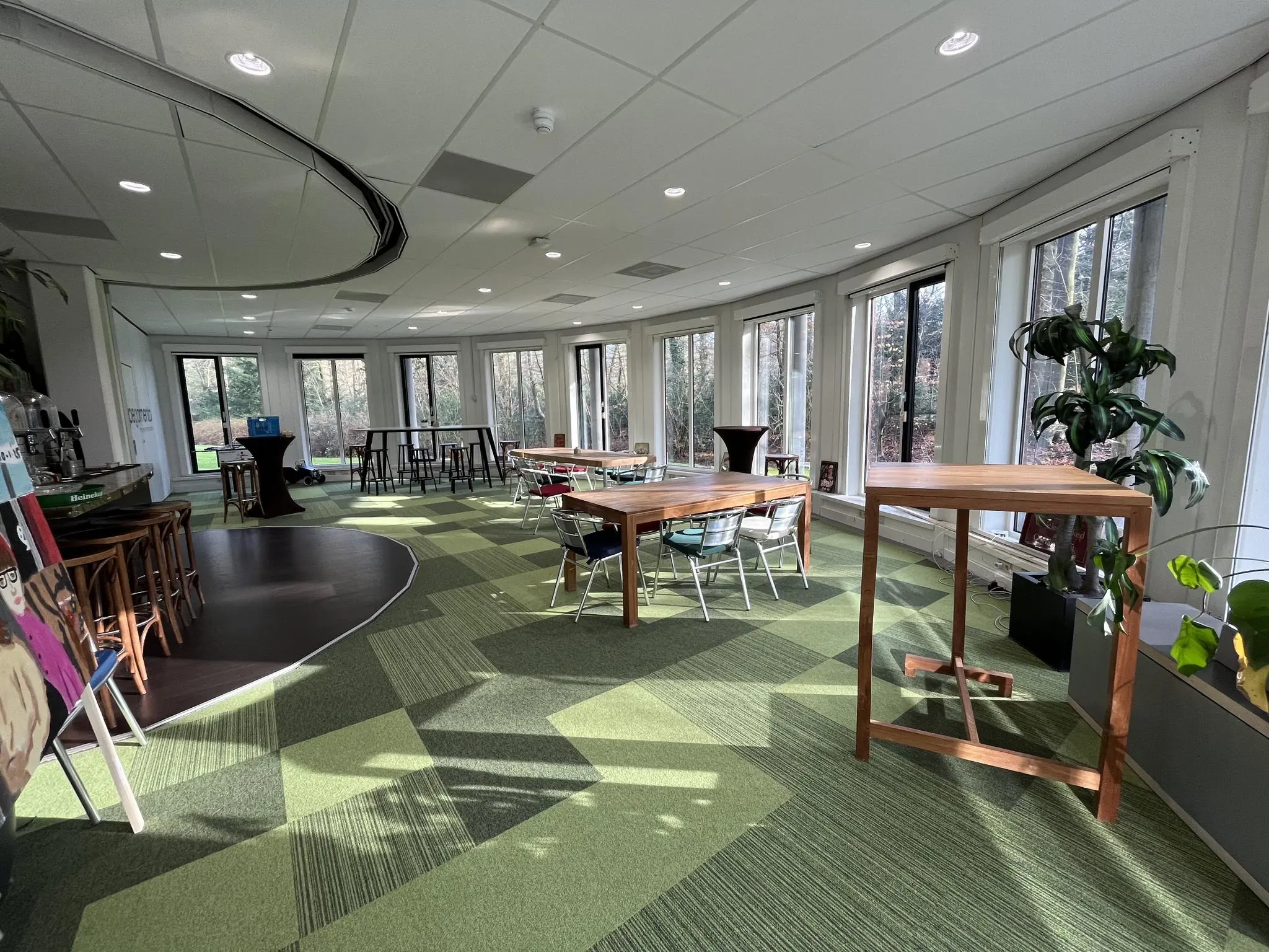 Lichte, moderne vergaderruimte aan de Arnhemse Bovenweg met grote ramen, groene vloer en houten meubilair.